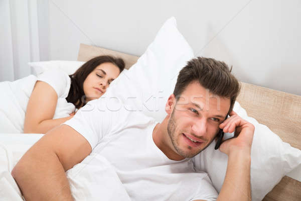 男 話し 携帯電話 妻 寝 ベッド ストックフォト © AndreyPopov