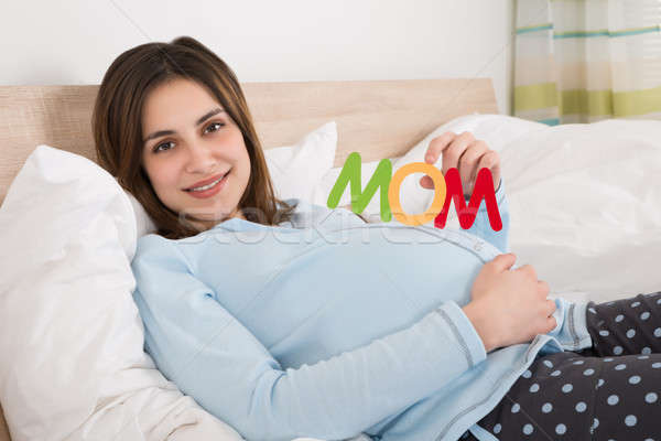 Pregnant Woman With Text Mom Lying On Bed Stock photo © AndreyPopov
