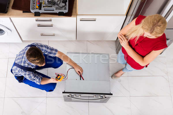 Male Worker Repairing Oven Using Multimeter In Kitchen Stock photo © AndreyPopov