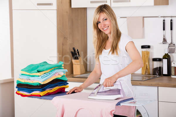 Smiling Woman Ironing Clothes With Electric Iron stock photo