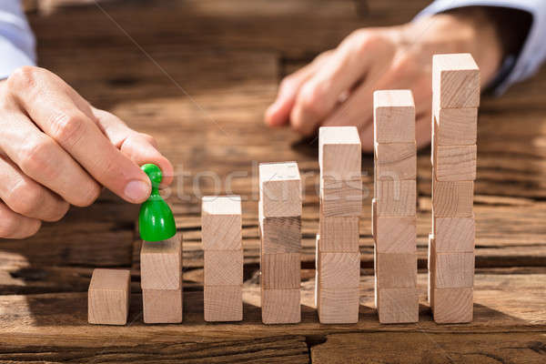 Businessman Placing The Green Figure On Block Stack Stock photo © AndreyPopov