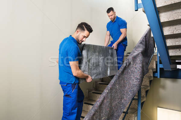 Stock photo: Two Movers Carrying Furniture On Staircase
