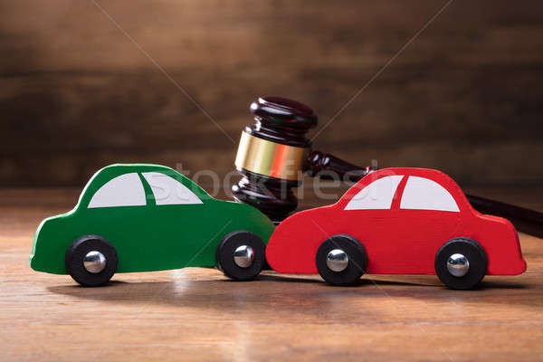 Collision Of Wooden Two Toy Cars In Front Of Gavel Stock photo © AndreyPopov