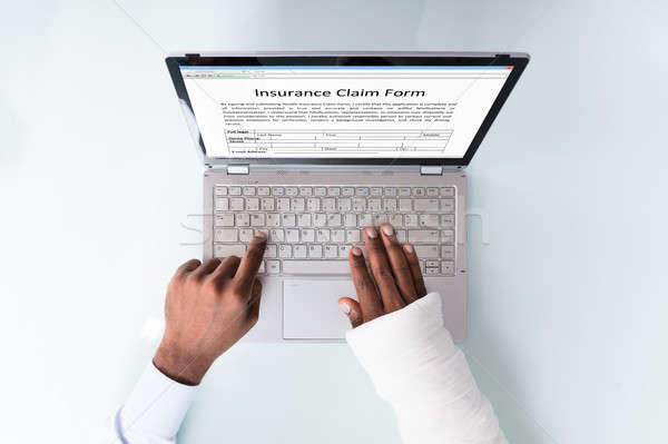 Businessman With Bandage Hand Filling Insurance Claim Form Stock photo © AndreyPopov