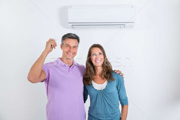 Happy Couple Standing In Front Of Air Conditioner Stock photo © AndreyPopov