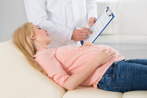 Midsection Of Doctor Writing Notes By Pregnant Woman In Hospital Stock photo © AndreyPopov