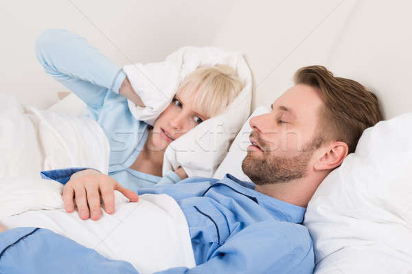 Woman Covering Her Ears With Pillow While Man Snoring Stock photo © AndreyPopov