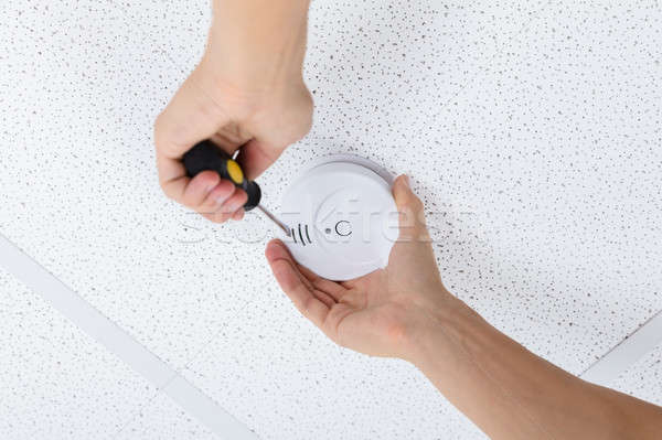 Person's Hand Using Screwdriver To Install Smoke Detector Stock photo © AndreyPopov