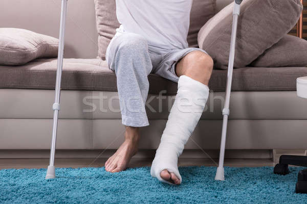 Man With Broken Leg Getting Up From Sofa Stock photo © AndreyPopov