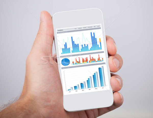 Hand Holding Mobile Phone With Financial Charts Stock photo © AndreyPopov