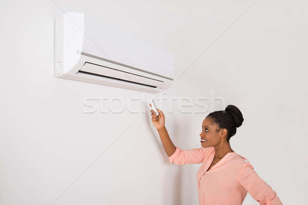 Smiling Woman Operating Air Conditioner Stock photo © AndreyPopov