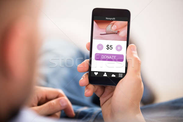 Hand Holding Mobile Phone With Donation App Stock photo © AndreyPopov