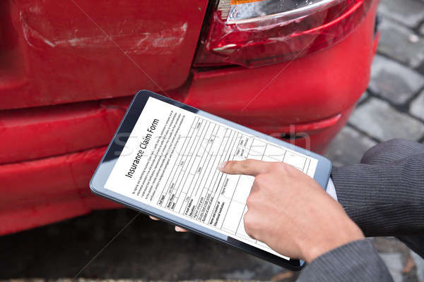 Stock photo: Insurance Agent Filling Insurance Claim Form On Digital Tablet