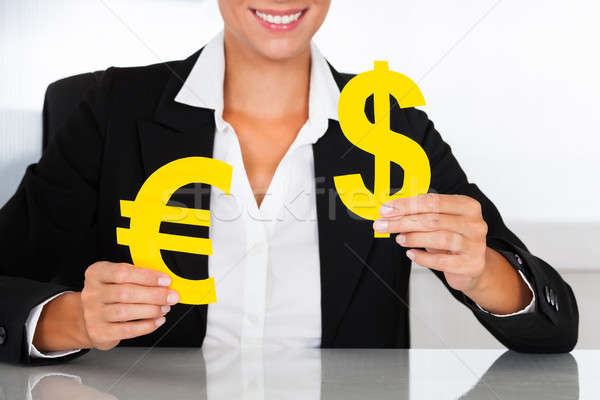 Businesswoman Holding Euro And Dollar Sign At Desk Stock photo © AndreyPopov