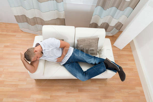Hombre sufrimiento estómago dolor joven sofá Foto stock © AndreyPopov