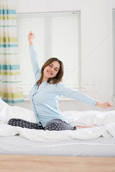Woman Stretching Her Arms On Bed Stock photo © AndreyPopov