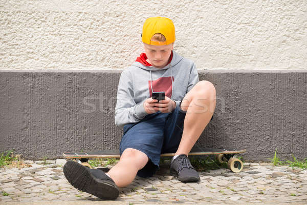 Jongen vergadering skateboard mobiele telefoon telefoon muur Stockfoto © AndreyPopov