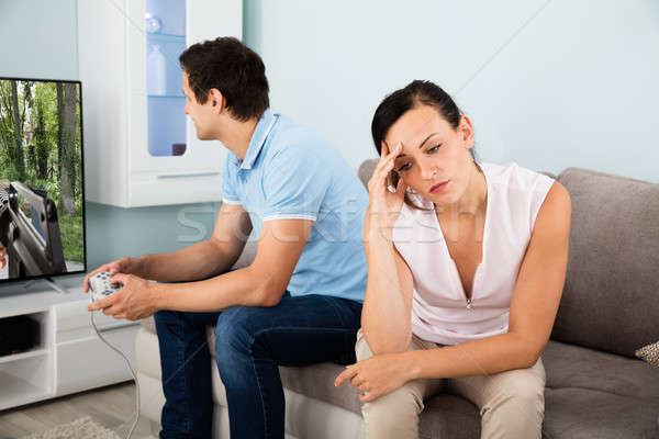 Sad Woman Sitting Beside A Man Addicted To Videogame Stock photo © AndreyPopov