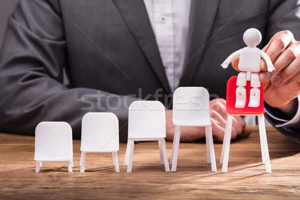 Businessperson Placing Human Figure On Red Chair Stock photo © AndreyPopov