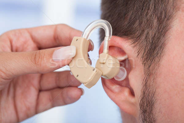 Doctor Inserting Hearing Aid In Man's Ear Stock photo © AndreyPopov