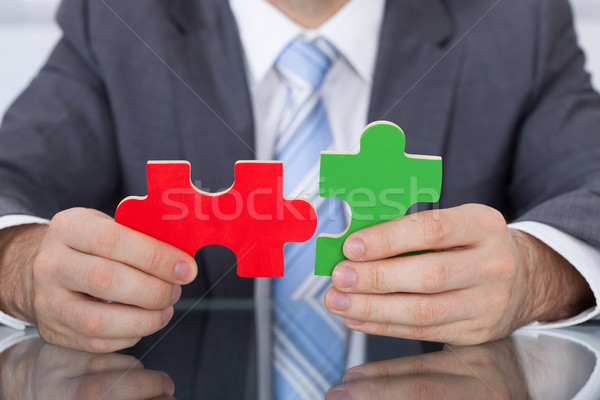 Businessman Fitting Two Puzzle Pieces Together Stock photo © AndreyPopov