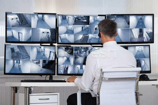 Security System Operator Looking At CCTV Footage At Desk Stock photo © AndreyPopov
