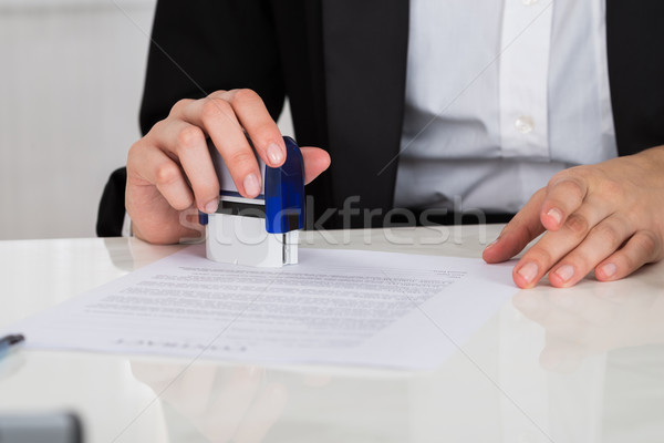 Businesswoman Stamping Contract Document At Desk Stock photo © AndreyPopov