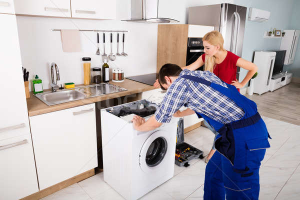 Stock photo: Male Worker Repairing Washer In Kitchen Room