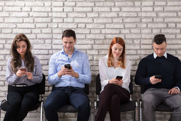 Pessoas de negócios celular jovem sessão cadeira parede de tijolos Foto stock © AndreyPopov
