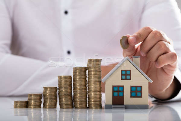 Businessman holding coin over house model Stock photo © AndreyPopov
