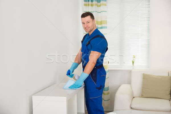 Smiling Janitor Cleaning Shelf With Sponge At Home Stock photo © AndreyPopov