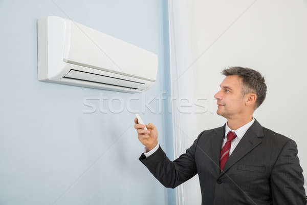 Businessman Using Remote Control To Operate Air Conditioner Stock photo © AndreyPopov