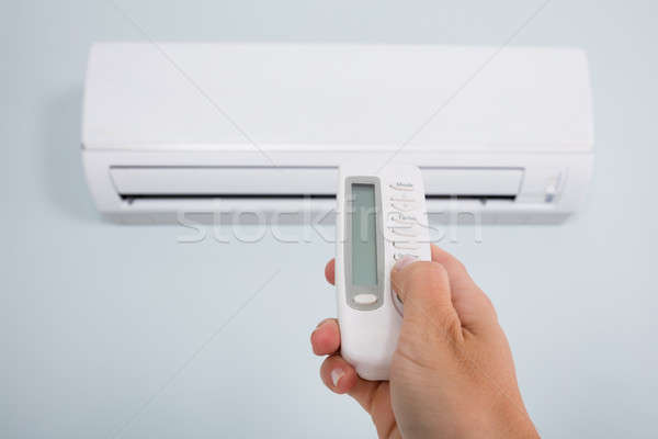 Person Operating Air Conditioner With Remote Control Stock photo © AndreyPopov