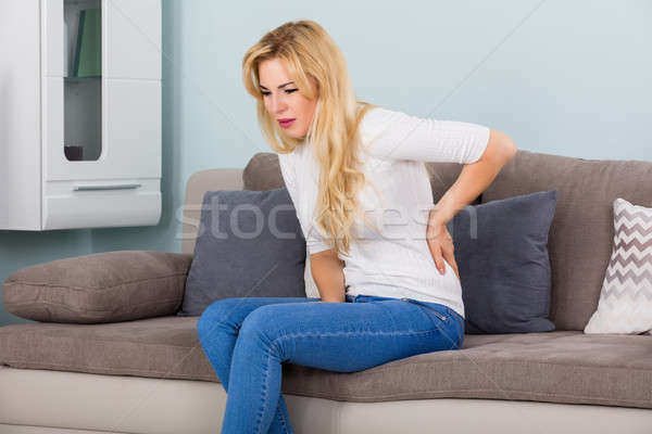 Vrouw lijden rugpijn jonge vrouw vergadering sofa Stockfoto © AndreyPopov