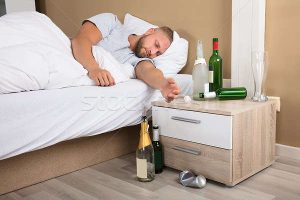 Junger Mann schlafen Bett Bier Flaschen Nachttisch Stock foto © AndreyPopov