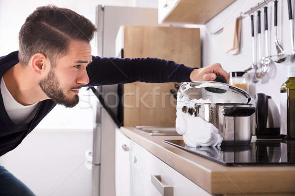 Man Looking At Spilling Out Boiled Milk From Utensil Stock photo © AndreyPopov
