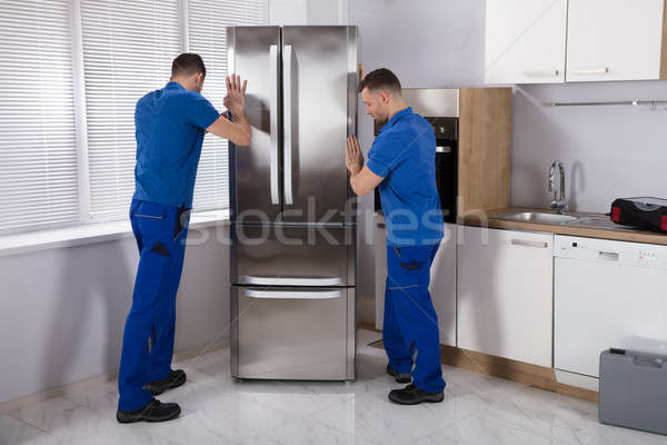 Two Movers Placing Refrigerator In Kitchen Stock photo © AndreyPopov