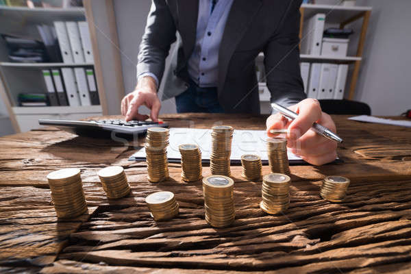 Businessperson Calculating Stacked Coins Stock photo © AndreyPopov