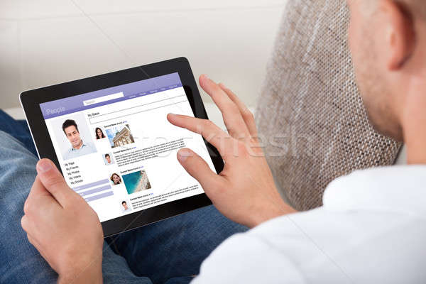 Man looking at personal profiles on a tablet Stock photo © AndreyPopov