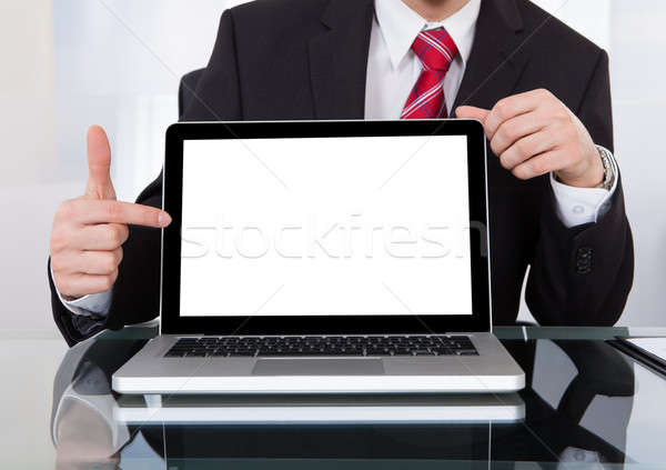 Confident Businessman Displaying Laptop At Desk Stock photo © AndreyPopov