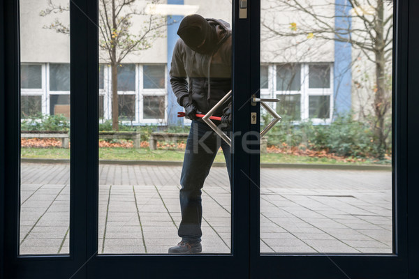 Stock photo: Hooded Man Using Crowbar To Open Glass Door