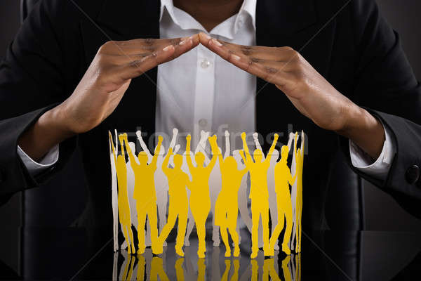 Businessperson Hands Protecting Paper Cut Out Of Human Figure Stock photo © AndreyPopov