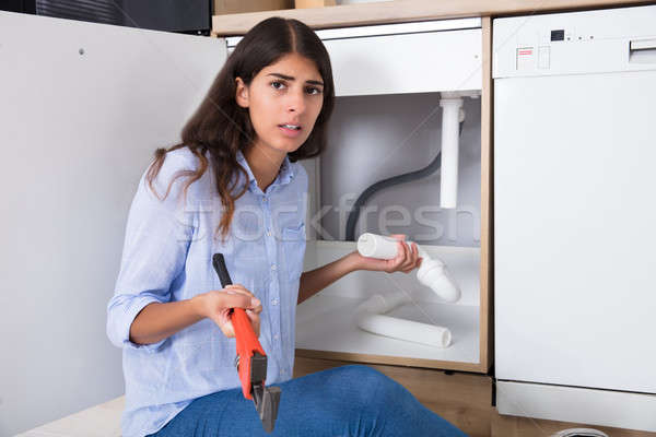 Stock photo: Woman Holding Sink Pipe And Monkey Wrench