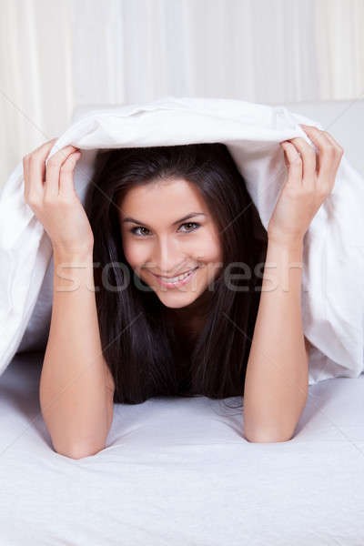 Smiling woman lying in bed Stock photo © AndreyPopov