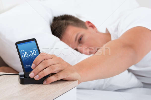 Uomo sveglia cellulare giovane letto schermo Foto d'archivio © AndreyPopov