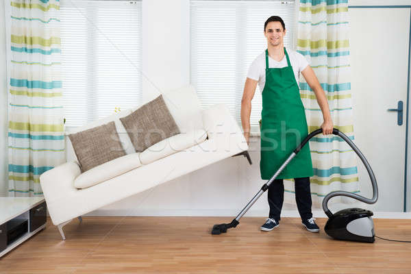 Homem sofá limpeza piso aspirador de pó Foto stock © AndreyPopov