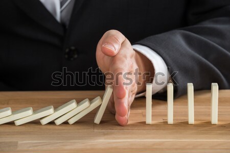 Businessman Hand Stopping Dominoes From Falling On Desk Stock photo © AndreyPopov
