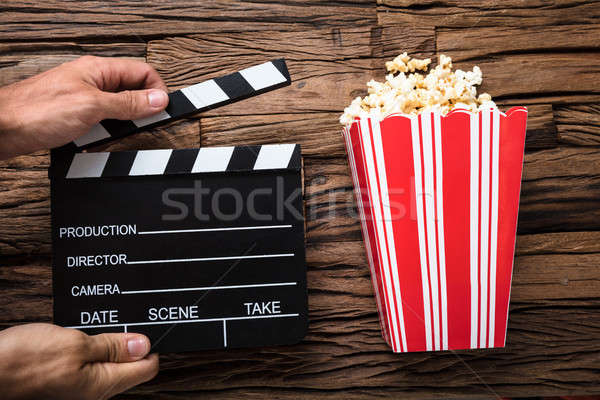 Stock photo: Hands Holding Clapperboard By Popcorn On Wood