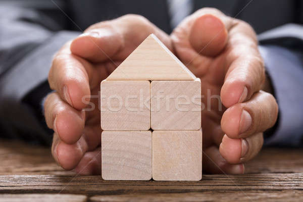 Businessman Covering Model Home Made From Wooden Blocks Stock photo © AndreyPopov