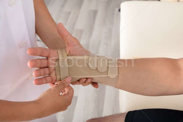Orthopedist Fixing Plaster On Injured Person's Hand Stock photo © AndreyPopov